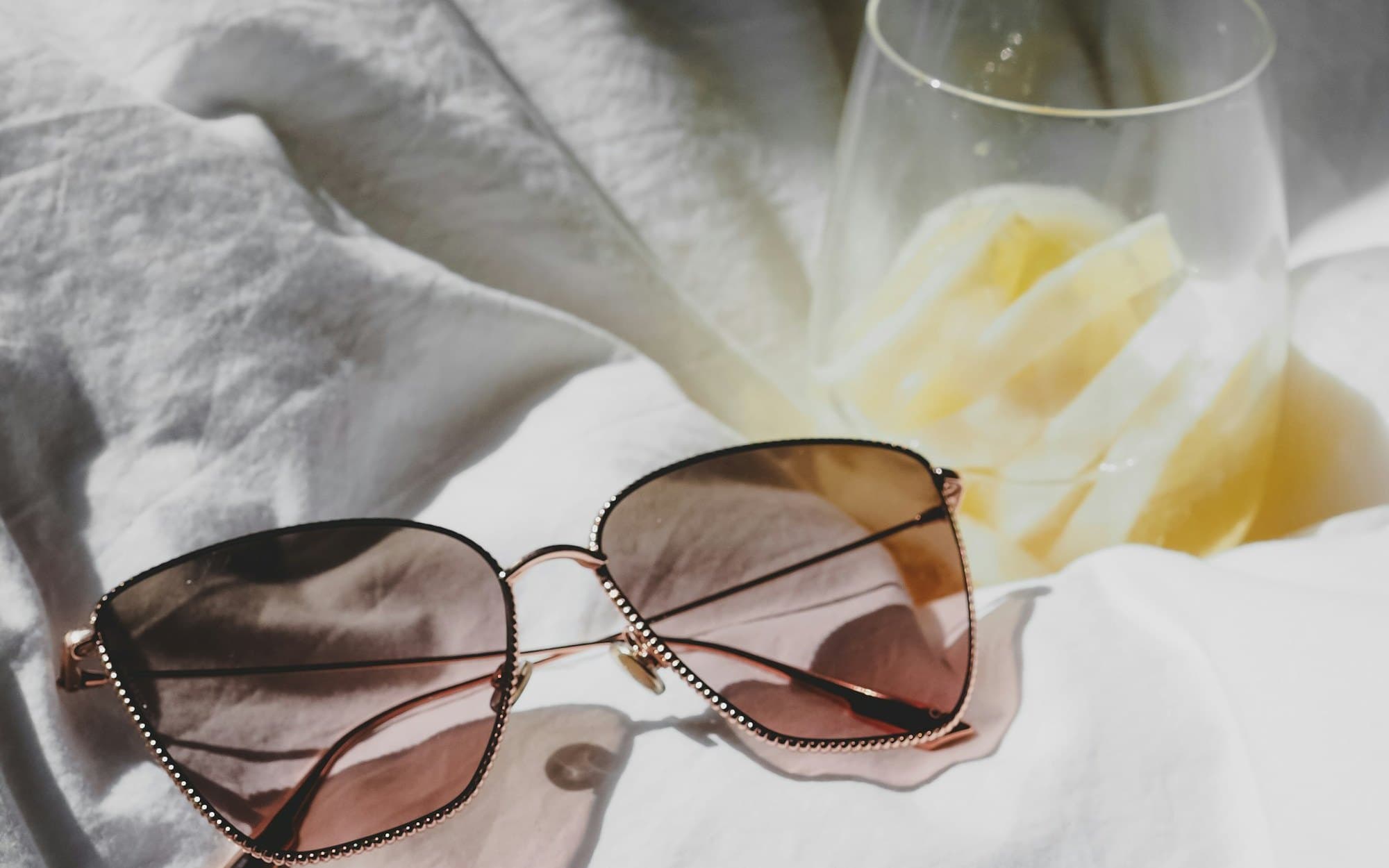 Gold-framed sunglasses resting on white linen