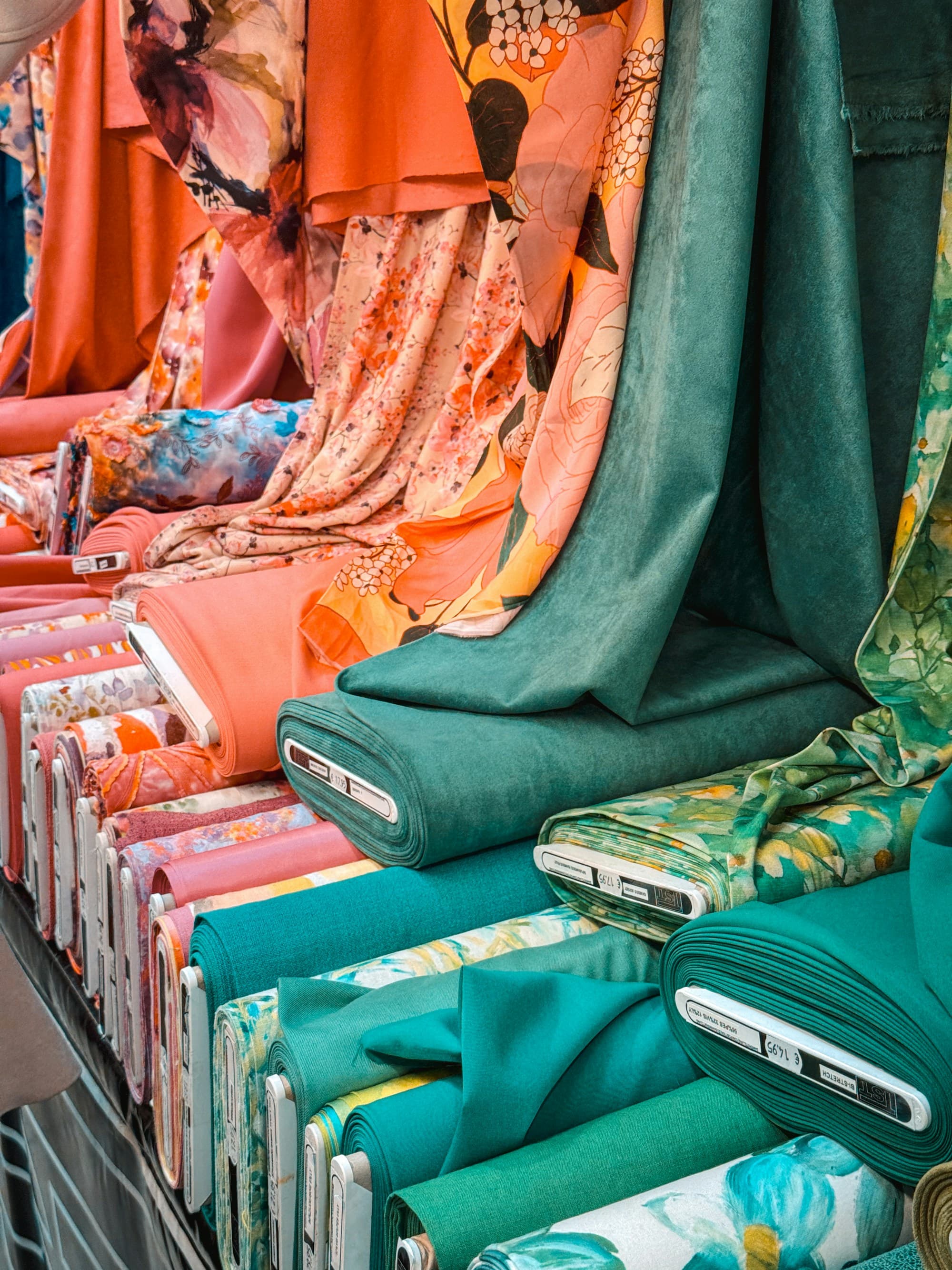 Rolls of printed and plain fabric stacked in a market stall